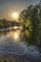 River Flowing at Sunset with Sunburst and Tree Reflection Scenery photo