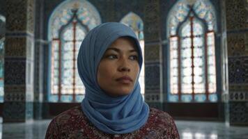 Woman Wearing Hijab Standing in Decorated Mosque Looking Thoughtfully Ahead photo