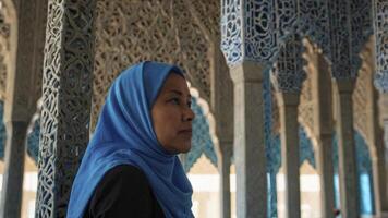Woman Wearing Hijab Looking Thoughtfully Amidst Ornate Columns in Historic Building photo
