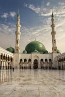 Medina Mosque with Green Dome and Tall Minarets Against Cloudy Sky photo