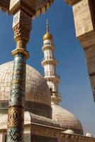 Viewing Mosque Domes and Minaret Through Ornate Archway on Clear Day photo