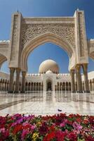 Sheikh Zayed Mosque View Through Ornate Arch with Bright Colored Flowers photo