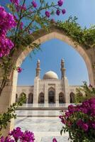 Mosque Seen Through Floral Archway with Towers Against Blue Sky photo