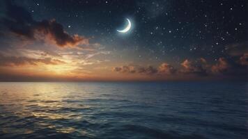 Ocean at Night with Crescent Moon Stars and Glowing Sunset photo