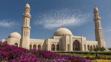 Grand Mosque Architecture with Minarets and Floral Gardens Under Blue Sky photo