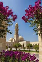 Mosque with Tower Framed by Pink Flowers and Green Trees on Sunny Day photo