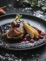 Roasted Duck Leg with Pear and Cranberries on Black Plate photo
