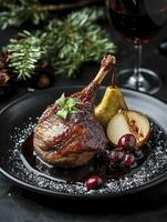 Roasted Duck Leg Garnished with Pears and Cranberries on Black Plate photo