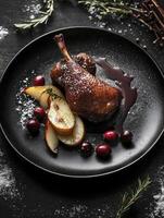 Roasted Duck Leg with Pear and Cranberries on Dark Plate photo