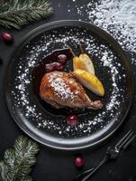 Roasted Duck Leg with Pears Cranberries and Powdered Sugar on Black Plate photo