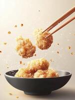 Picking Golden Fried Chicken Pieces with Chopsticks Over a Bowl photo