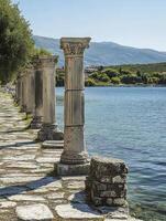 Walking Along Ancient Columns by the Seaside with Mountain View Backdrop photo