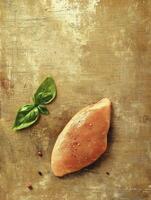 Preparing Raw Chicken Breast with Basil and Pepper on Rustic Surface photo