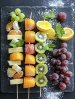 Arrangement of Delicious Fruit Skewers on a Slate Platter with Grapes photo
