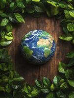 Earth globe surrounded by green leaves on wooden background photo