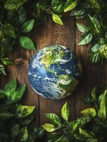 Earth Globe Surrounded by Green Leaves on Rustic Wooden Background photo