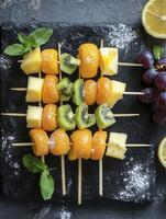 Fruit Skewers with Citrus and Kiwi on a Dark Stone Board photo