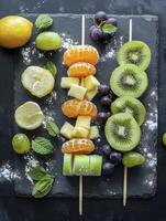 Arranging Fresh Fruit Skewers on Slate Board with Lemon and Mint photo