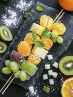 Preparing Fresh Fruit Skewers with Cheese and Grapes on Black Slate photo