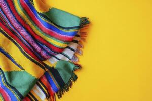 Colorful Striped Blanket with Fringes on a Yellow Background for Copy Space photo