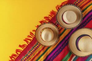 Three Sombrero Hats on Colorful Blanket Against Yellow Background Overhead Shot photo