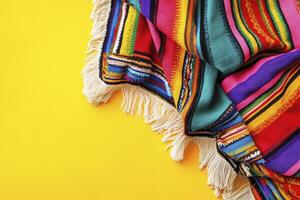Colorful Striped Blanket with Fringe on Yellow Background Overhead View photo
