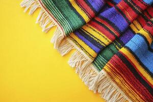 Colorful Striped Textile with Fringe on Bright Yellow Background photo