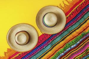 Two Straw Sombrero Hats and Colorful Serape on Yellow Background photo