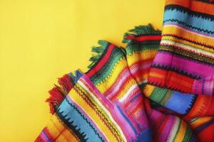 Folded Colorful Textile with Fringe on Vibrant Yellow Background Overhead Shot photo