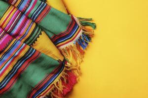 Colorful Striped Blanket with Fringe on Yellow Background Texture Overlay photo