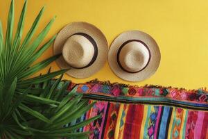 Straw Hats with Colorful Blanket and Palm Leaf on Yellow Backdrop photo