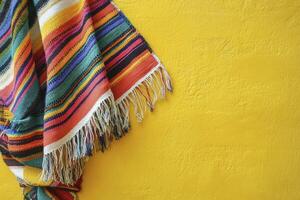 Striped Mexican Poncho Displayed Against a Vibrant Yellow Textured Background photo