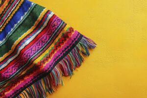 Vibrant Andean Textile with Fringe on Yellow Background, Cultural Craft photo