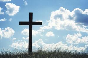 Silhouette of Christian Cross on Grassy Hill with Cloudy Blue Sky photo