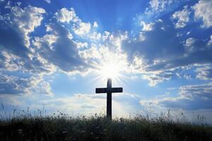 Cross Silhouette Against Bright Sky with Sun Rays and Grass Field photo