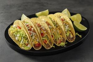 Delicious Tacos on a Black Plate with Lime Wedges Ready to Eat photo