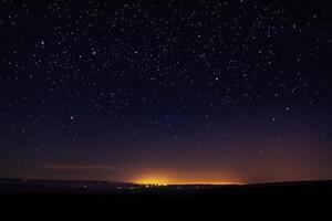Starry Night Sky Over City Lights Glowing on the Horizon photo