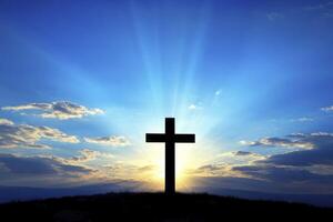 Silhouette of Cross at Sunset Against a Bright Blue Sky Background photo