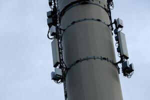 Steel telecommunication tower rises against a cloudy sky, adorned with photo