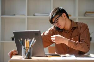 Businessman consulting on phone while using a tablet and reviewing financial documents. photo