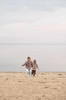 The siblings walk side by side on the beach, their checkered coats swaying in the ocean breeze. photo