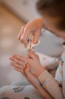 Small, rounded-tip baby scissors trim the delicate fingernails of a tiny hand photo