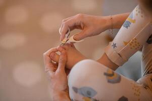 A mother carefully trims her babys toenails using small, child-friendly manicure scissors. photo