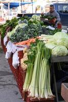 The scent of herbs and earth fills the air as a vendor weighs a gigantic leek for a smiling customer at the organic market. photo
