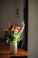 A beautifully arranged bouquet adds a natural touch to the minimalist wooden table in the morning glow. photo