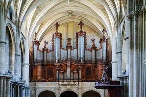 The grand organ, adorned with exquisite carvings and multiple golden pipes, stands majestically in the church, enhancing the architectural beauty of the vaulted ceiling and the overall ambiance. photo