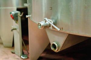 The image showcases a close-up view of a stainless steel tank with a valve, commonly used in food and beverage processing, highlighting its industrial design and functionality. photo