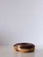 A chocolate glazed doughnut with a bite taken out of it photo