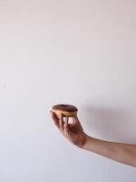 A hand holding a chocolate glazed doughnut photo