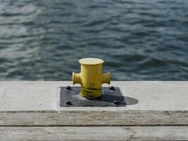A yellow mooring bollard on a pier with a blurred water surface in the background. photo